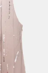 Vestido corto color rosa pálido con lentejuelas plateadas dispuestas en líneas verticales. Presenta un escote asimétrico con un detalle de tirante ancho tipo foulard que se ata al cuello.