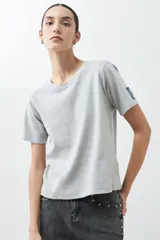Remera de manga corta, cuello redondo y calce regular, color verde agua jaspeado. Presenta un pequeño parche bordado en la manga izquierda.