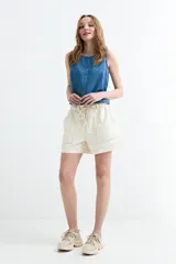Top de denim sin mangas, color crudo, con cuello redondo y costura central visible.
