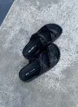 Sandalias negras de cuero con dos tiras anchas cruzadas sobre el empeine.