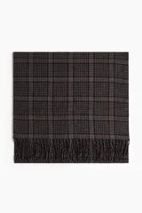 Bufanda de diseño rectangular con estampado a cuadros en tonos marrón y negro, terminada con flecos en los extremos.