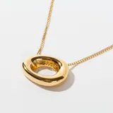 Collar dorado con cadena fina y dije ovalado con abertura central.