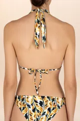 Top de bikini con estampado abstracto en tonos amarillo mostaza, negro y blanco. Diseño de cuello halter con tiras ajustables y detalle metálico dorado con forma de hoja en la unión de las copas.