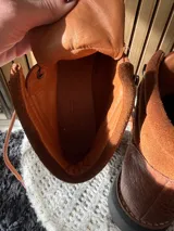 Botas Saura de cuero y gamuza en color tostado, con cordones frontales, suela gruesa y diseño tipo borceguí.