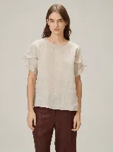 Blusa de lino color crudo, con cuello redondo y mangas cortas adornadas con volados dobles.
