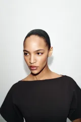 Vestido midi de color negro, confeccionado en tejido de punto con cuello barco y manga corta. Presenta un diseño ajustado en el torso que se combina con una falda inferior con vuelo y acabado evasé.