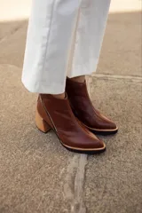 Botinetas de cuero con textura reptil en color bordó, con cierre lateral metálico y taco cuadrado de madera en tono natural.