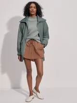 Campera larga color verde con cuello acanalado, cierre de doble sentido, bolsillos de parche grandes, cintura interior ajustable y puños con borde con volados.