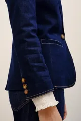 Blazer de denim azul oscuro con solapas de muesca, cierre frontal de un botón y bolsillos con solapa.