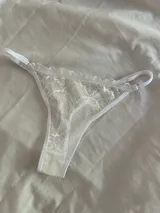 Bombacha tipo tanga de encaje blanco con terminaciones en elástico y breteles regulables.