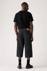 Pantalón capri de denim negro con corte amplio, tiro alto y cinturón de tela con hebilla metálica.