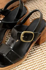 Sandalias de cuero color marrón con tiras anchas y hebilla plateada. Taco de madera.