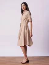 Vestido camisero blanco de algodón con cuello con solapa, delantera abotonada, mangas 3/4 regulables con presilla y botón, y cintura con lazo de ajuste.