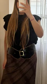 Cinto tipo faja ancha de cuero negro, con bordes festoneados y costura decorativa en color camel. Hebilla cuadrada dorada.