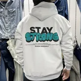 Canguro blanco oversize de algodón con felpa, con capucha y cordón ajustable. Estampa en la espalda con la frase "Stay Strong" en negro y turquesa, y texto inferior con la marca "Duxon Originals".