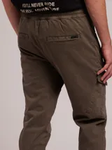 Pantalon cargo de sarga con cintura elástica y cordón de ajuste. Presenta bolsillos laterales tipo cargo con solapa y bolsillos frontales con cierre. Diseño con puños elásticos en los tobillos.