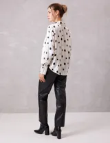 Camisa de satén con estampado de rectángulos negros sobre fondo blanco. Presenta cuello clásico con solapa, cierre frontal con botones metálicos y mangas largas con puños rectos.