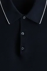 Remera polo azul marino en punto texturizado de mezcla de algodón, con cuello y bordes de mangas acanalados con ribete blanco, tapeta con tres botones y manga corta.