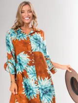 Vestido camisero largo con estampado floral en tonos rojos y negros, con cuello camisero, abotonadura frontal y mangas largas con puños abotonados.