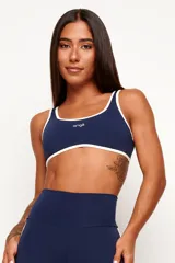 Top deportivo de poliamida color azul marino, de modelado slim y ajuste ceñido al cuerpo. Presenta escote redondo y tiras en color blanco contrastante que recorren los bordes superior e inferior, con el logo de la marca estampado en el centro del pecho.