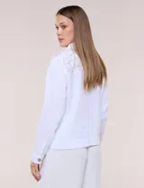 Camperita corta de calce recto color blanco, confeccionada en tejido liviano con textura arrugada. Cuenta con cuello con solapa, diseño estampado sobre los hombros y canesú, cierre frontal con botones de madera rústicos, bolsillos superiores en el pecho con solapa y mangas largas con puño abotonado.