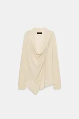 Chaqueta de punto fino color beige, con escote fluido y drapeado, manga larga y cierre frontal cruzado.