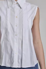 Camisa azul marino sin mangas con cuello clásico, abotonada al frente y detalle de plisados verticales en el pecho.