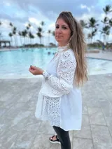 Camisa blanca de broderie con cuello mao, mangas largas amplias y cierre frontal con botones.