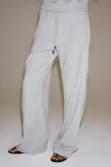 Pantalón ancho de felpa en color gris melange, con tiro medio y cintura elástica ajustable con cordón. Cuenta con bolsillos laterales ocultos en costura y diseño de pernera ancha.