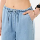 Pantalón vaquero de corte ancho y relajado, color azul claro, con cintura elástica fruncida y cordón ajustable.