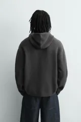 Chaqueta de punto de corte relajado, color azul, con capucha, cierre frontal con cremallera y acabados en rib en puños y bajo.
