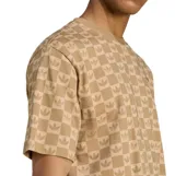 Remera Adidas de manga corta con cuello redondo, confeccionada en tejido con estampado de tablero y logo del trébol repetido en tono beige.