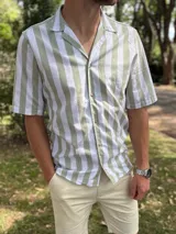 Camisa de manga corta con diseño a rayas verticales en tonos verde militar y blanco, cuello camisero con solapa abierta y cierre frontal con botones.