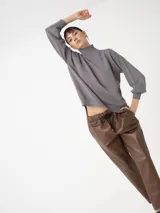 Sweater azul de cuello alto, con mangas amplias y puños ajustados.