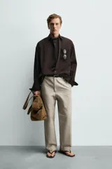Pantalón relaxed fit para hombre, confeccionado en tejido con mezcla de algodón y lino, en color beige. Presenta bolsillos laterales, bolsillos traseros de plastrón y cierre frontal con cremallera y botón.