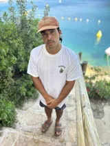 Remera blanca de algodón con cuello redondo y estampado en la espalda con imágenes de cogollos de marihuana y texto "BROKERS HIGH QUALITY GOODS".