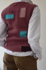 Chaleco tejido a mano en lana merino, con escote en V, cierre frontal de botones de madera y diseño con detalles geométricos de colores.