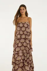 Vestido largo bordó con estampado paisley, escote recto y tirantes finos. Presenta un diseño de múltiples volantes superpuestos con hilos metalizados que aportan movimiento y textura.