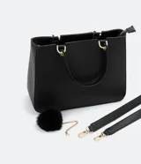Bolso satchel negro con correa de mano fija y correa bandolera desmontable. Incluye llavero de pompón.
