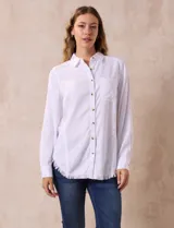 Camisa blanca de lyocell, marca Hester & Orchard. Tiene cuello con solapa, abertura central con botones, bolsillo aplicado en el pecho y ruedo desflecado.