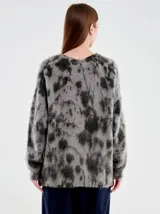 Cardigan largo de punto con escote en V y cierre frontal de botones. Presenta un diseño de calce relajado con patrón moteado en tonos gris y negro, confeccionado en una mezcla de lana y fibras sintéticas con textura suave.