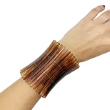 Pulsera ancha de resina color marrón con diseño de barras alargadas unidas por hilos elásticos.