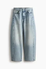 Jean de cinco bolsillos en denim de algodón rígido, con diseño de piernas curvas y volumen, de corte holgado desde la cadera hasta los muslos y ligeramente más ceñido en el bajo. Cintura clásica con cierre de botón y cremallera.