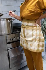 Delantal corto de algodón color crudo con teñido artesanal shibori en tonos marrones.