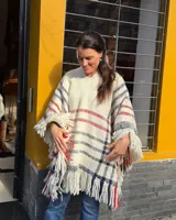 Poncho de lana merino tejido en telar de peine, color marfil con diseño a cuadros en tonos azul marino y rojo, terminado con flecos en el ruedo.