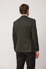 Blazer de corte slim fit en color marrón con textura jaspeada, cierre frontal de dos botones, solapas clásicas y bolsillo en el pecho con pañuelo decorativo.