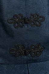 Top peplum sin mangas en color azul denim, con cuello mao y cierre frontal con alamares decorativos negros. Cuenta con un bajo acampanado con pliegues y cierre lateral con cremallera oculta.