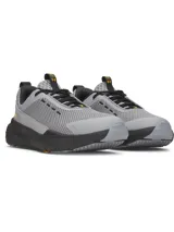 Championes de entrenamiento Under Armour Project Rock BSR 5, diseñados para estabilidad y flexibilidad. Presentan una parte superior de malla transpirable en color gris con detalles en negro y amarillo, mediasuela Charged Cushioning para amortiguación reactiva y tecnología UA TriBase para mayor contacto con el suelo.