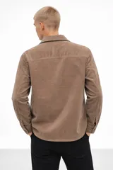 Sobrecamisa de pana color negro, de corte holgado, con cuello clásico, cierre frontal de botones y bolsillo en el pecho.