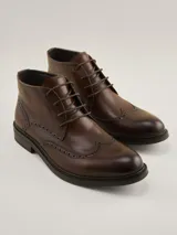 Botas de cuero marrón oscuro estilo brogue, con cordones y suela baja.